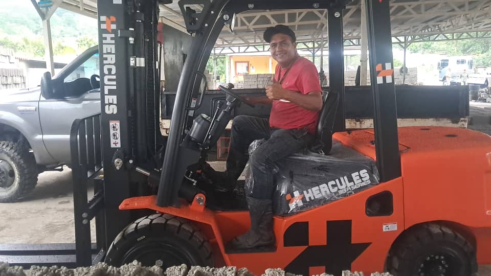 Cliente sonriente con el pulgar arriba, sentado en su montacargas Hércules recién entregado